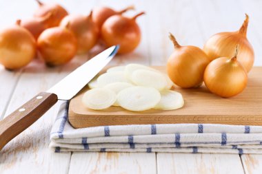 Beyaz ahşap bir masada, doğranmış sarı soğan, seçici bir odak noktası..