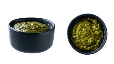 Beyaz arka planda izole edilmiş fesleğen soslu siyah seramik kase..