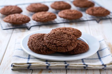 Taze pişmiş Amerikan çikolatalı kurabiyeleri siyah tel askıda soğuyor, açık mutfak masasında, seçici bir odak noktası var..