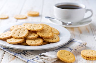 Tuzlu krakerler yuvarlak şekiller ve açık mutfak masasında kahve, seçici bir odak.