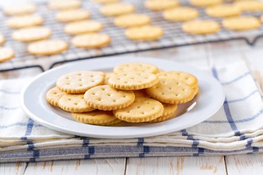 Taze pişmiş buğday yuvarlak krakerleri siyah tel askıda soğutuluyor, açık mutfak masasında, seçici bir odak noktası var..