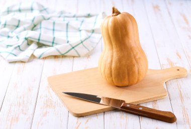 Beyaz ahşap masadaki kesme tahtasındaki balkabağı şeklindeki şişe şeklindeki balkabağı, metin için alanı kopyala.