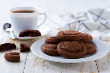 Nefis çikolatalı kek kurabiyeleri ve açık mutfak masasında kahve, seçici bir odak noktası..