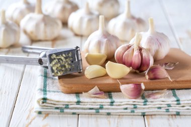 Sarımsaklı karanfil. Beyaz ahşap masada soyulmuş sarımsak soğanları..