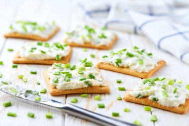 Sağlıklı kahvaltı kavramı, krem peynirli bisküviler ve ahşap masada taze kesilmiş soğanlar..