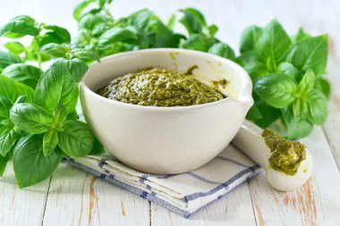 Tahta bir masada taze yeşil fesleğenle ev yapımı pesto sosu..