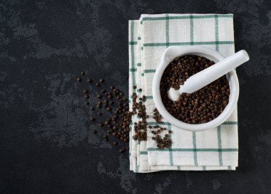 Havan topu ve tokmak ya da siyah bir mutfak masasında siyah biberli kase, üst manzara.