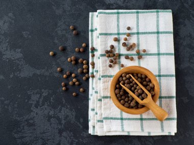 Tüm baharatlar ya da Jamaika biberi tohumları siyah taş bir masada, seçici bir odak noktasında..