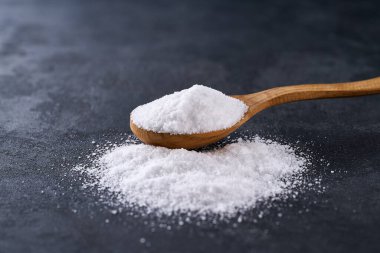 Tahta kaşıkta tuzlanmış deniz siyah bir masada, seçici bir odak noktası..