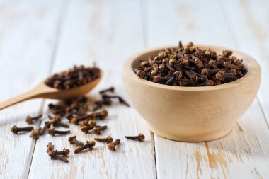 Tahta kasede karanfil baharatı beyaz ahşap bir masada, seçici bir odak.