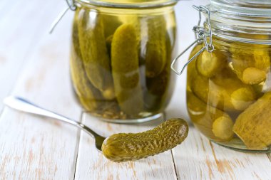 Şeffaf cam kasede salatalık turşusu beyaz ahşap bir masada, seçici bir odak noktası..