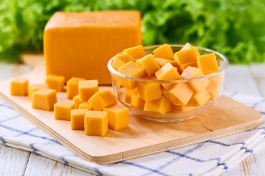 Beyaz ahşap bir masada çedar peyniri küpleri, seçici odak.