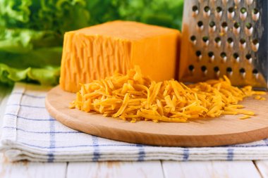 Çedar peyniri, beyaz ahşap bir masada yakın çekim olarak, seçici bir odak noktası.