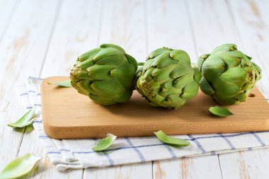 Taze enginar, mutfak masasında çiğ, yenilebilir sinara çiçeği tomurcukları, organik İtalyan sebzeleri..