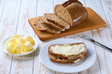 Düz kompozisyon ve lezzetli çavdar ekmeği ve tereyağı ahşap masada..