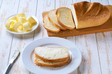 Düz kompozisyon ve dilimlenmiş buğday ekmeği ve tereyağı ahşap masada..