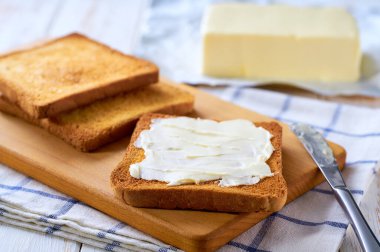 Kızarmış ekmeğe tereyağı sürüp açık mutfak masasına serpiştirdim..