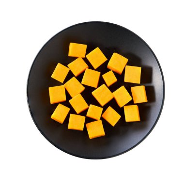 Beyaz arka planda izole edilmiş kırmızı çedar peyniri küpleriyle siyah seramik kase..