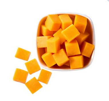 Beyaz arka planda izole edilmiş kırmızı çedar peyniri küpleriyle siyah seramik kase..