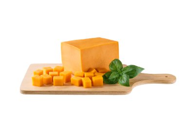 Beyaz arka planda izole edilmiş yeşil fesleğenli çedar peyniri küpleriyle kesme tahtası..