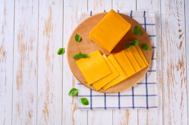 Kesme tahtasının üzerinde bir dilim çedar peyniri ve metin için kopyalama alanı. Üst görünüm.