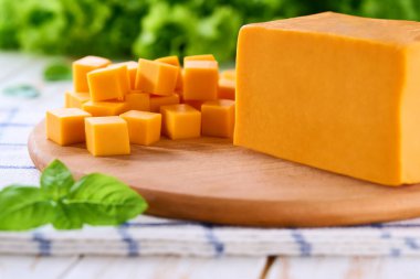 Açık mutfak masasında çedar peyniri küp şeklinde kesilmiş, seçici bir odak noktası..