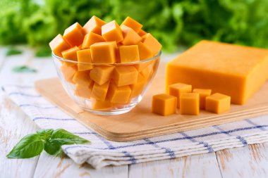 Çedar peyniri şeffaf cam bir kâsede mutfak masasında küp şeklinde kesilmiş, seçici bir odak noktası var..
