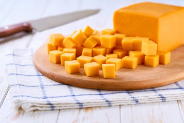 Açık mutfak masasında çedar peyniri küp şeklinde kesilmiş, seçici bir odak noktası..