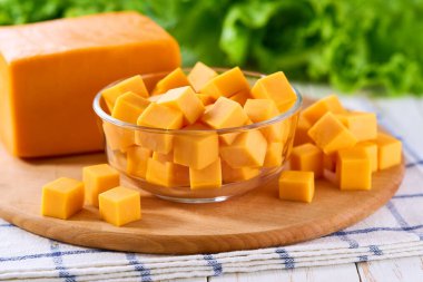 Çedar peyniri şeffaf cam bir kâsede mutfak masasında küp şeklinde kesilmiş, seçici bir odak noktası var..