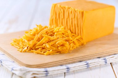 Çedar peyniri, beyaz ahşap bir masada yakın çekim olarak, seçici bir odak noktası.