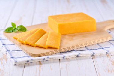 Açık mutfak masasında dilimlenmiş çedar peyniri, seçici bir odaklanma..