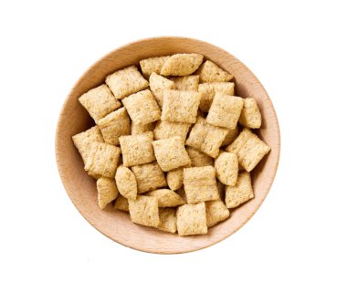 Beyaz arka planda izole edilmiş ahşap bir kasedeki mısır yastıkları, üst manzara. Tahta bir kasede mısır gevreği..