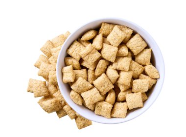 Beyaz arka planda izole edilmiş seramik tabaktan mısır yastıkları dökülüyor. Üst Manzara. Çıtır mısır gevrekleri dökülüyor.