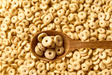 Yuvarlak yulaf tabanlı mısır gevreği ve mısır gevreğinden oluşan tahta bir kaşık. Metin için alanı kopyala.