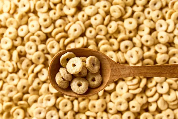 Yuvarlak yulaf tabanlı mısır gevreği ve mısır gevreğinden oluşan tahta bir kaşık. Metin için alanı kopyala.