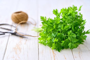 Hafif ahşap bir masada bir demet organik maydanoz, seçici bir odak.