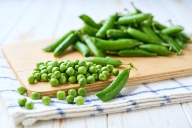 beyaz ahşap bir masada yeşil bezelye yığını, metin için boşluk kopyala.