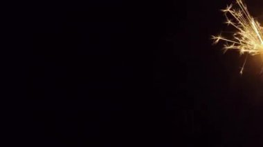 Siyah stüdyo arka planında kıvılcımlar yanıp sönüyor. Parlak Bengali havai fişekleri, karanlıkta altın kıvılcımlar saçan. Tatil kavramı, yeni yıl, parti, doğum günü. Kapatın. 4k