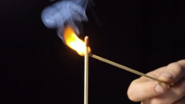 Siyah Arkaplanda Kibrit ve Alev 'i yakmak. Ağır çekim. Yakın plan. Bir sürü duman. Burns 'ün arkasında kömürleşmiş bir odun bırakmasından sonra 4K.