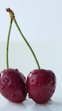 Beyaz arka planda iki kırmızı kiraz. 4 K döngüsel hareket