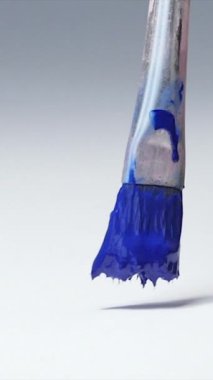 Boya fırçası tutan ve yağlı boya resim çizen sanatçıya yakın çekim. Tuvalin mavi rengini doldur. Adım adım..