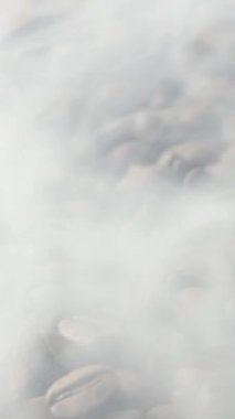 Kavrulmuş kahve çekirdeklerini yakından çek. Aromatik kahve çekirdekleri kahve çekirdeklerinden gelen kavrulmuş dumanlardır. Kızarmış tahıllar kahverengi bir torbanın üzerinde yatar. Ağır çekim. Döndürme kamerası.