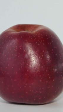 Close up fresh red apple on the table. Macro shot of a red apple. An apple rotates around its axis on a white background.