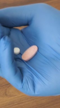 İki beyaz hap bir kadın avucuna bir kutu haptan düşüyor. Yakın plan.