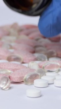 Balık yağı ve diğer vitaminlerle dolu Omega-3 sarı haplar beyaz kağıdın kırışık yüzeyine düşer. Makro. Doğal tıp kavramı. İlaç ve hap ara. Pembe beyaz sarı