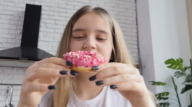 Renkli kremalı çörek yiyen ve gülümseyen bir kadının yakın çekimi.