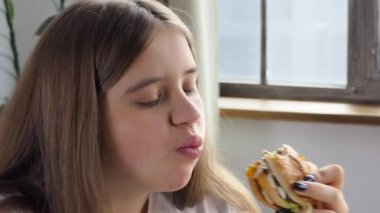 Girl eating a hamburger. close-up shot. Fast food eats. Burger in female hands. 4K