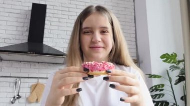 Donut yiyen güzel bir kadın tatlı tatlı tatların tadını çıkarıyor ve tatminle gülümsüyor.