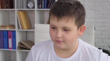 Schooler boyusing tablet computer for online education at home. Kid enjoys making school homework online, hand writing in textbook. 4K