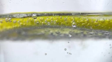 Slow Motion Macro shot of a lemon slice in water bubbles, Soft Drink with Ice, Bubbles, Mint and Lemon. Close Up Refreshment sparkles lemon soda and Cold Summer Drink 4K